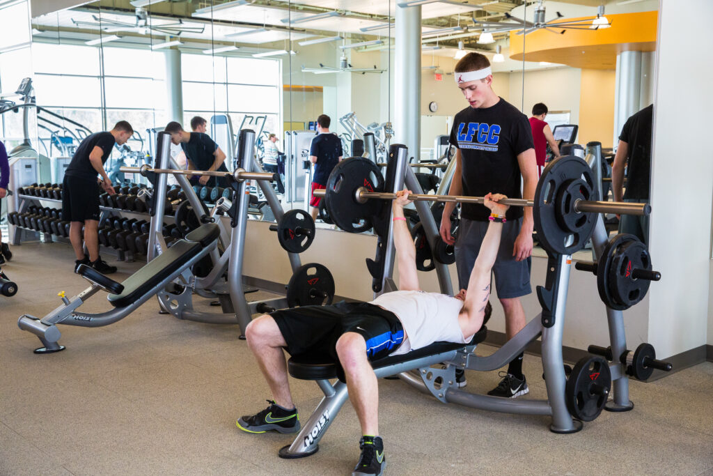 Student using a weight bench with another student spotting him