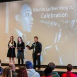 Three people on stage with a backdrop of Martin Luther King, Jr.