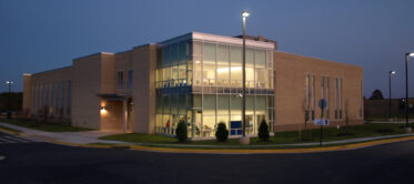a photograph of the science building taken at night with the moon in the sky