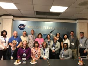 Group posing for a photo in front of a NASA Wallops Flight Facility sign