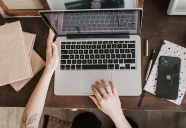a photograph of an open computer with two hands placed on the keyboard ready to type