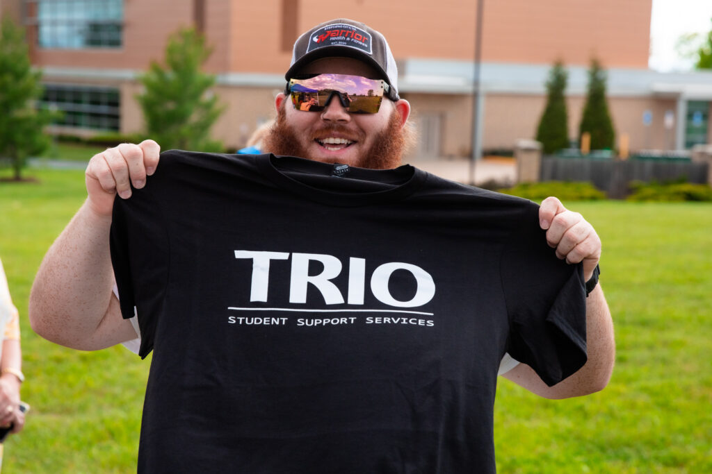 Trio student holding up shirt