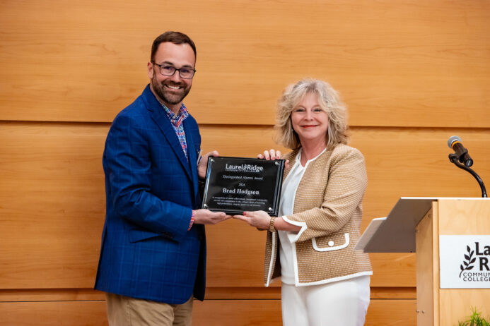 Brad Hodgson and Kimberly Blosser holding alumni award and smiling.
