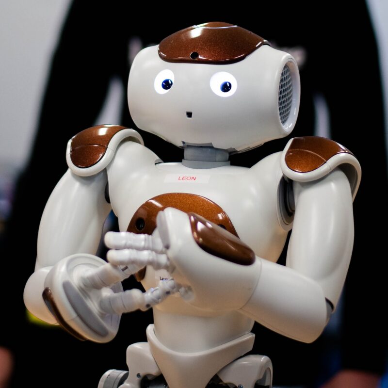 Small humanoid robot named "Leon" gestures with its hands during a demonstration.