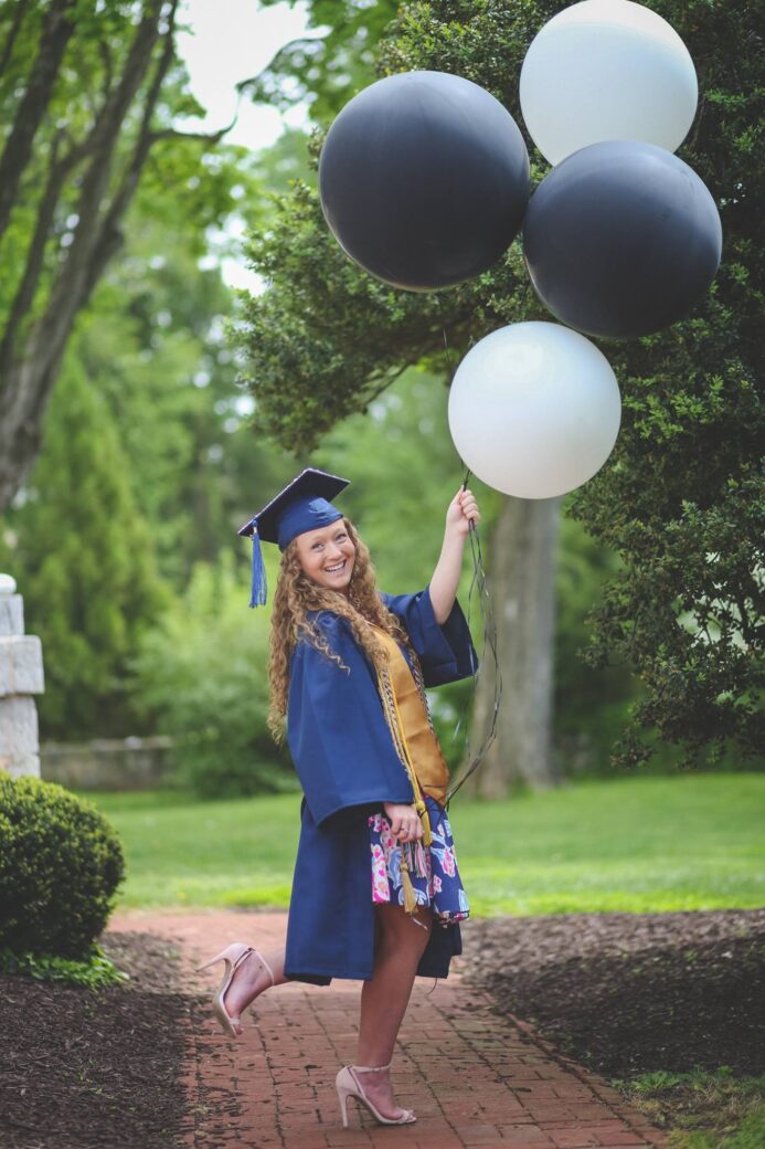 Sparber posing with balloons in graduation cap and gown