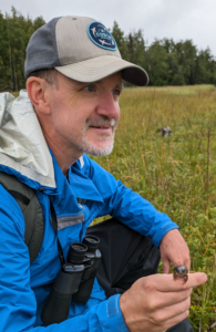 man in field with binoculars