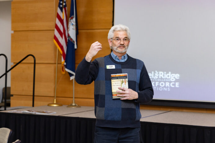 Baker holding a book and speaking at the Leadership Institute