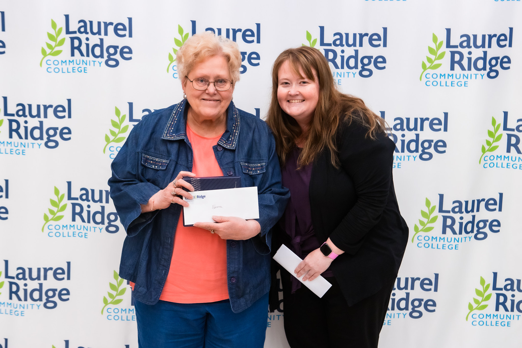 Two people posing in front of Laurel Ridge backdrop
