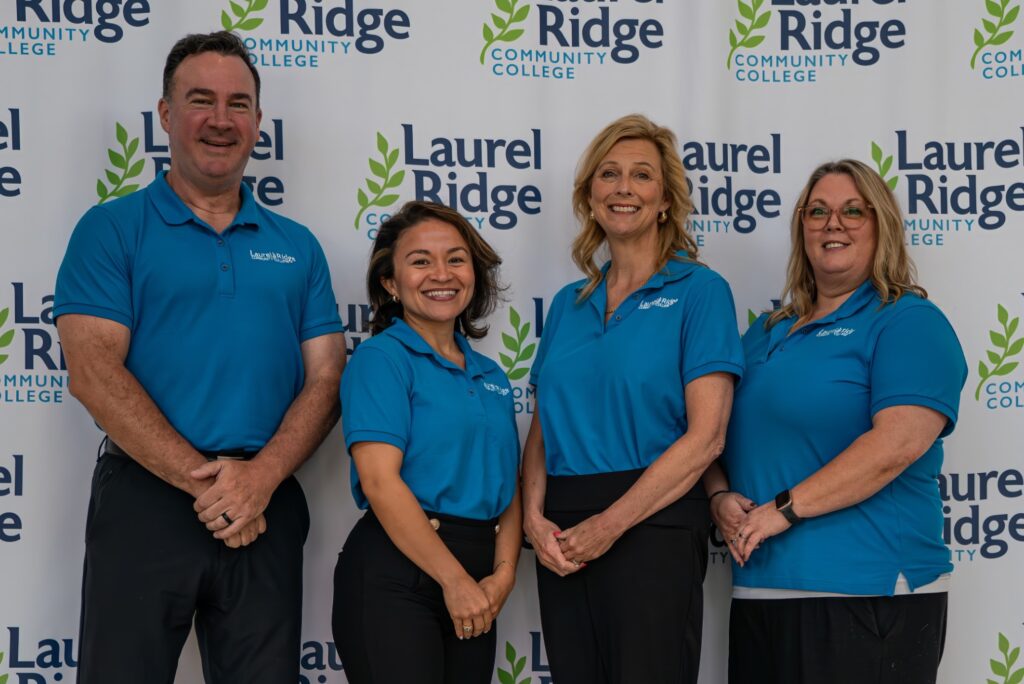A group of four people facing forward and smiling 