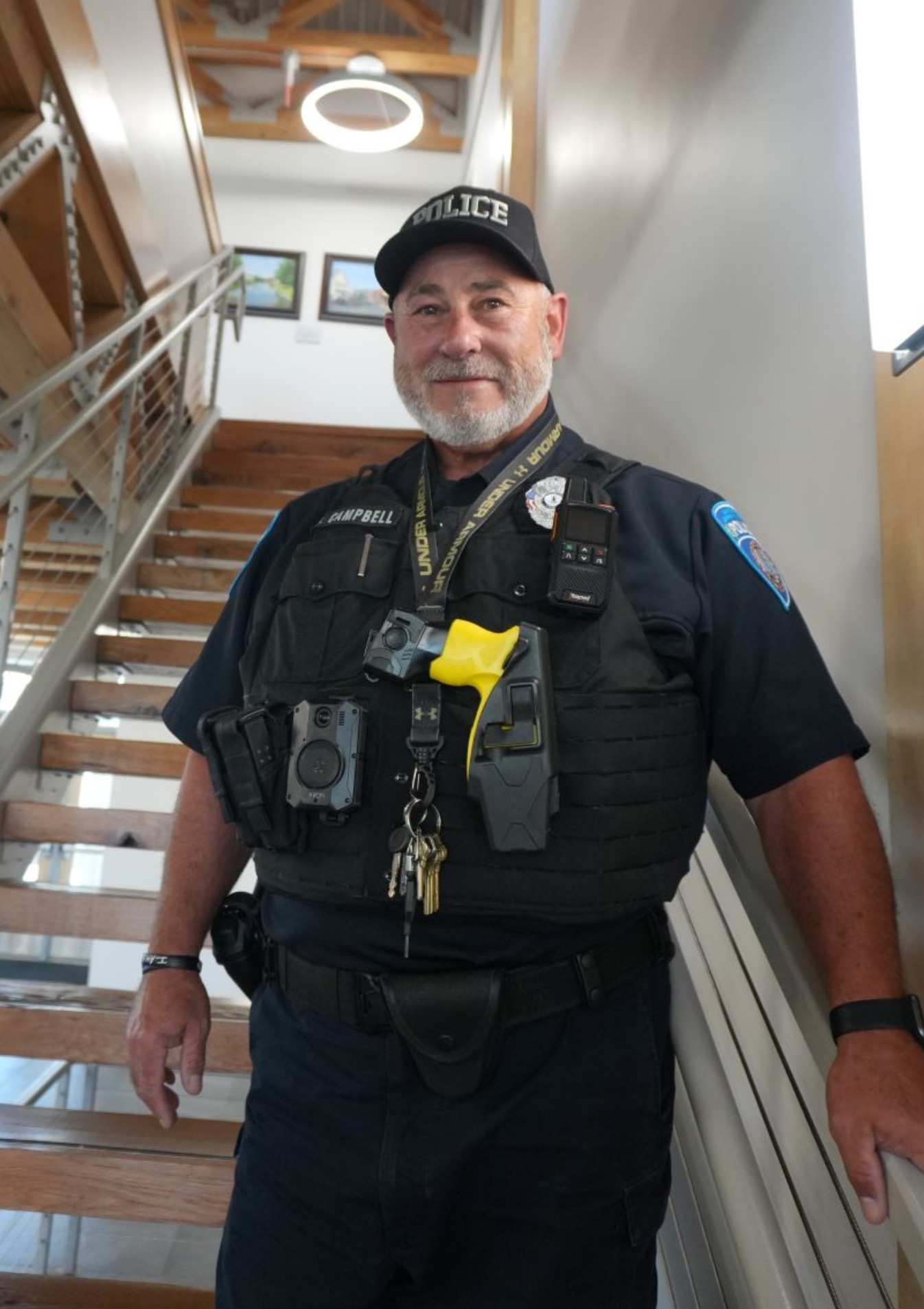 a photograph of a police officer standing on a set of stairs facing forward and smiling