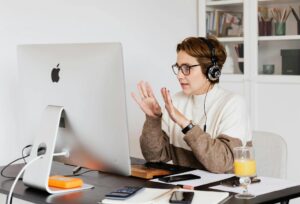 A woman using a computer and meeting online while wearing headphones