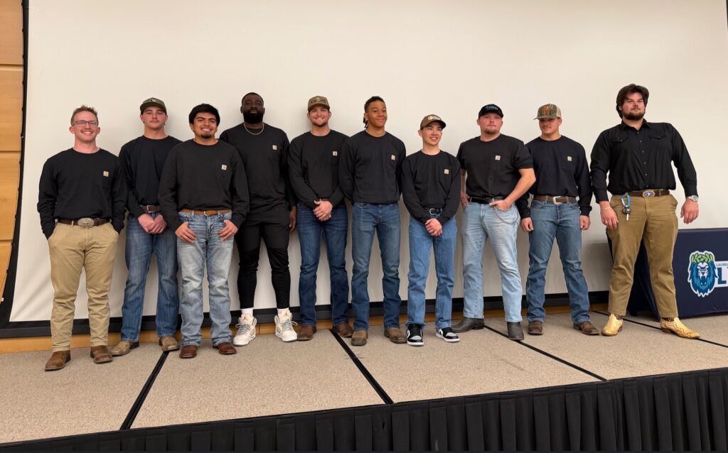 a row of men stand together on a stage smiling