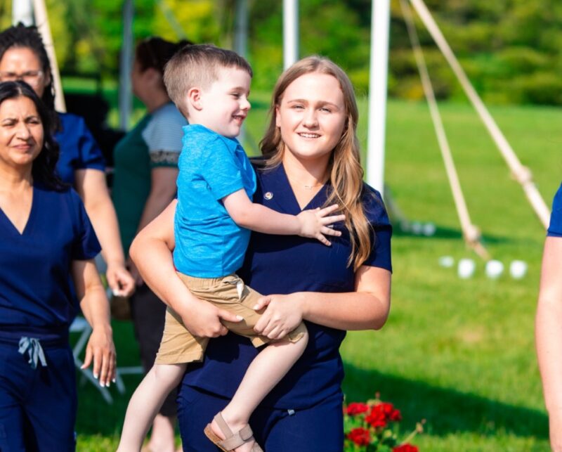 a photograph of a nursing student carrying her son in her arms