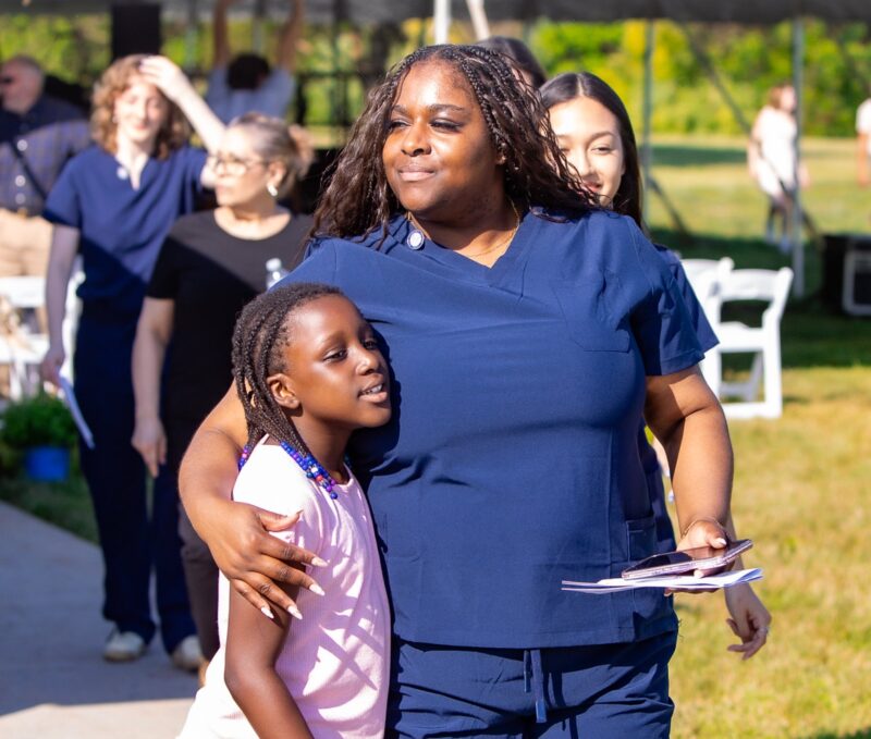 a photograph of a female nursing student with her arm around her child