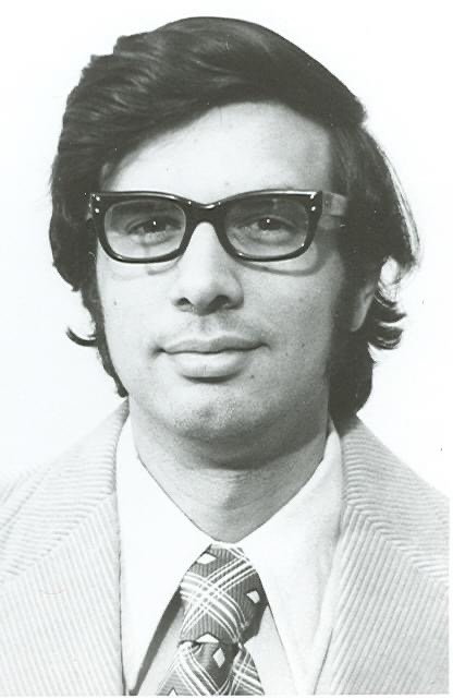 a black and white photograph of a male teacher wearing a suit and tie and glasses