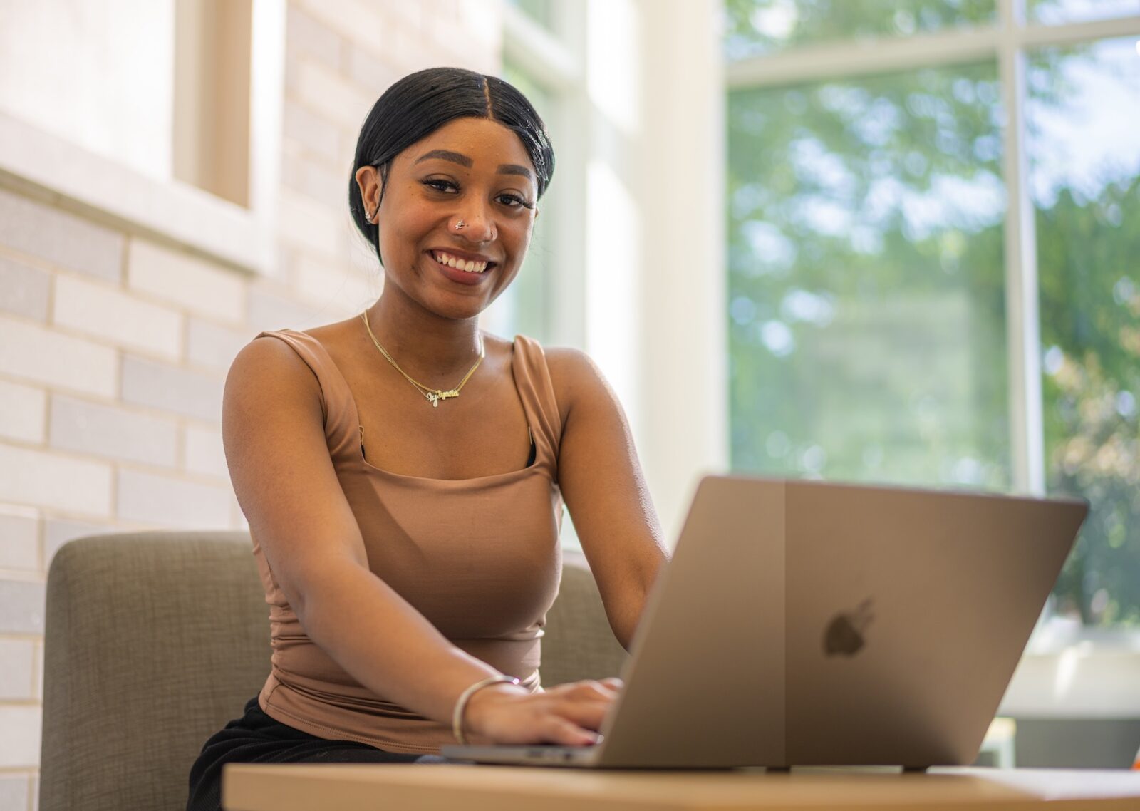 a female student using a laptop computer looking forward and smiling