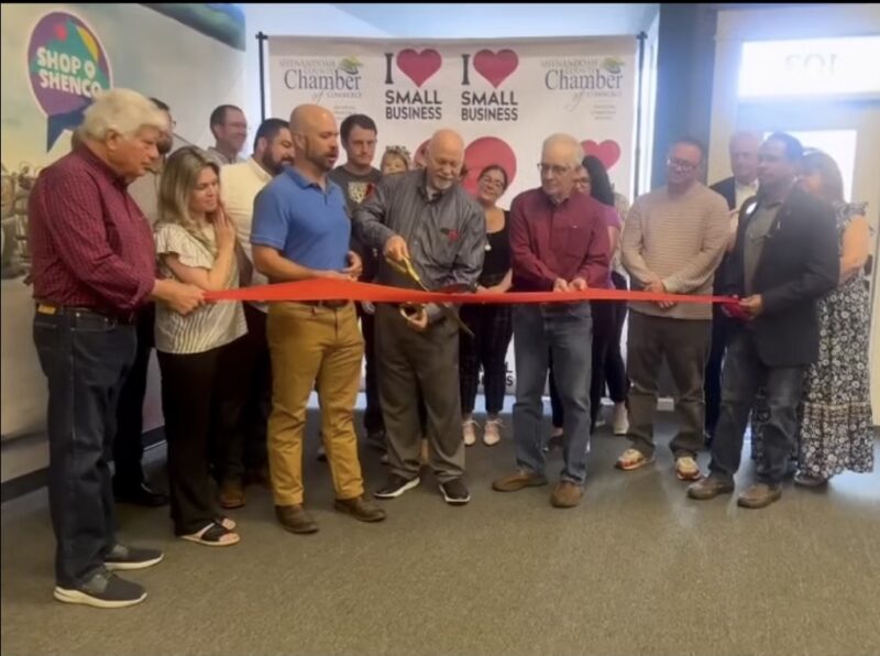 a group of people smile and clap as a ribbon is cut to celebrate an opening of a store