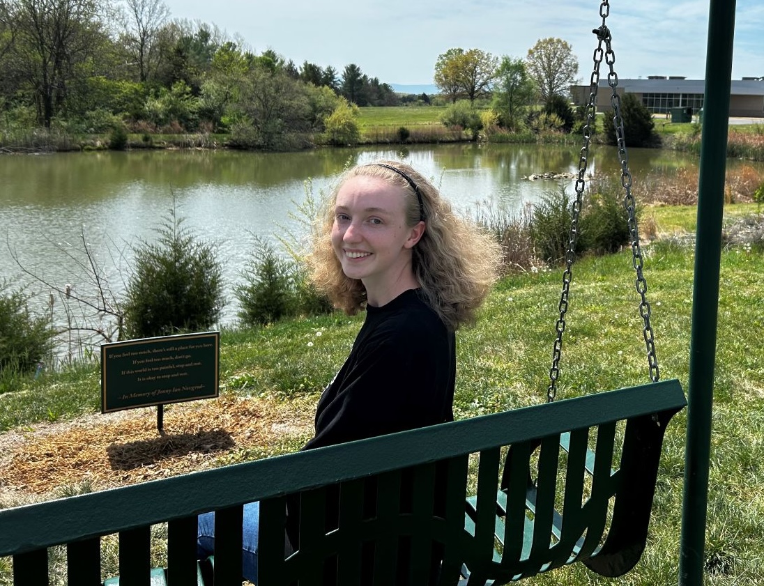 Mary smiling and sitting on a swing overlooking the pond on the Laurel Ridge campus