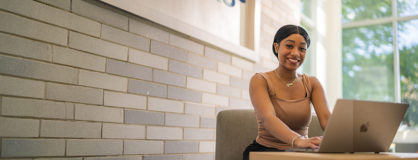smiling woman using computer laptop looking forward at the camera