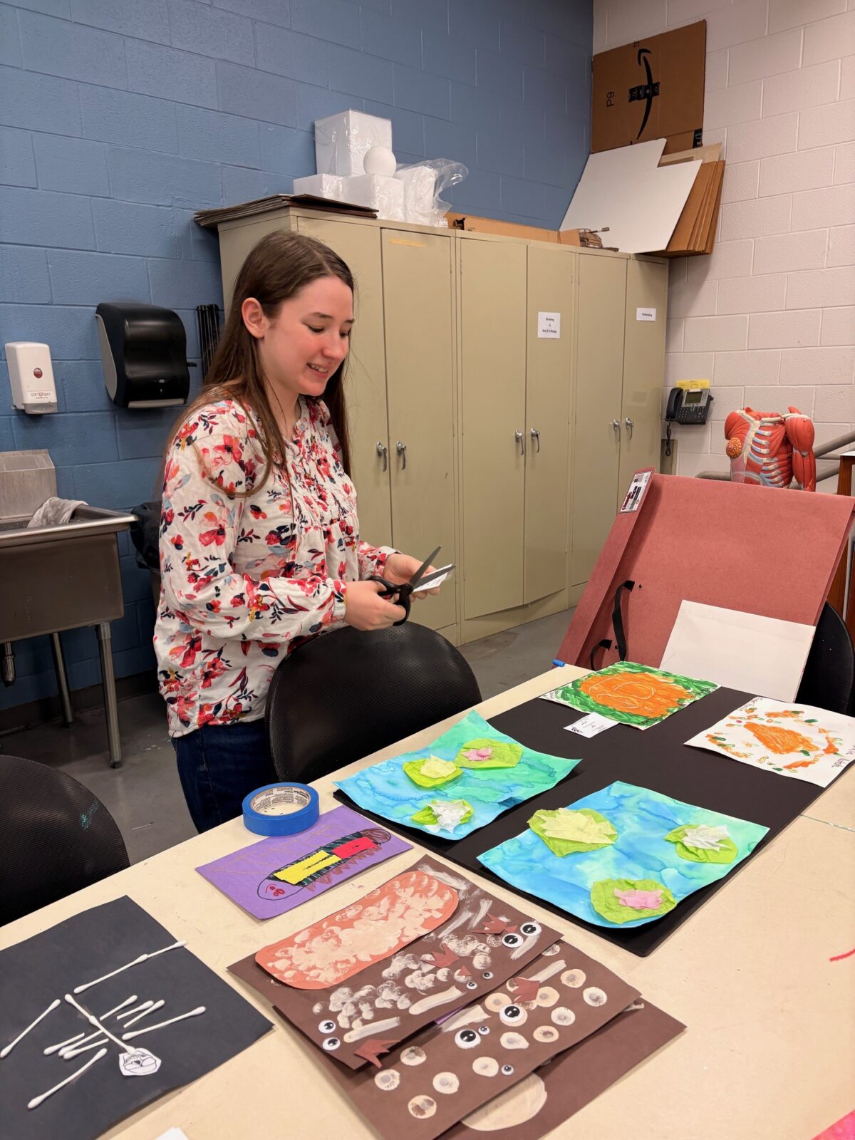 FEA student Chloe cutting paper materials while preparing artwork for the exhibit.