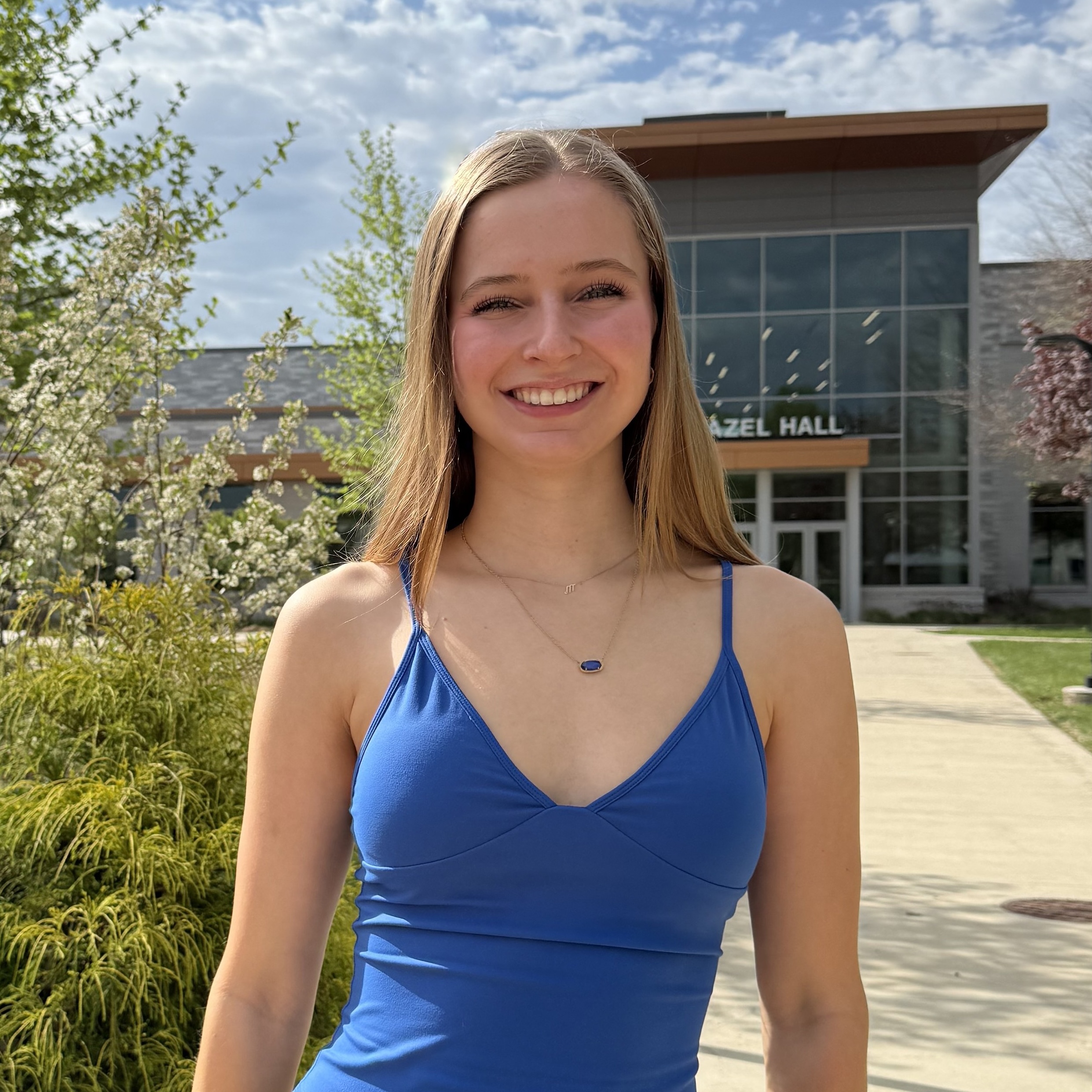 Mia Heller stands outside on a sunny day in front of the Hazel Hall building.