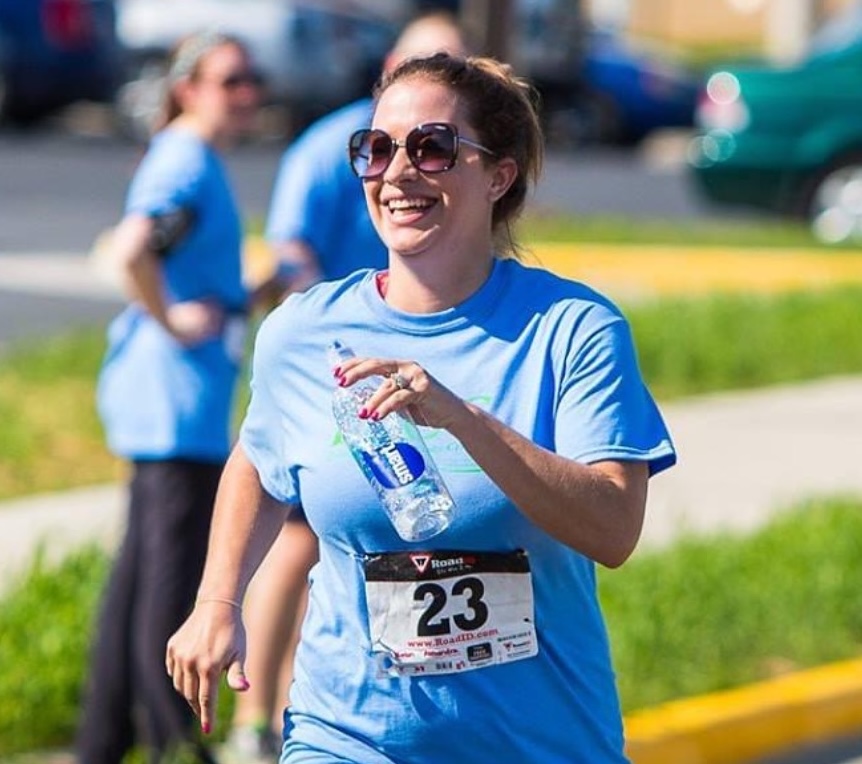 A woman running a 5k race with a big smile on her face
