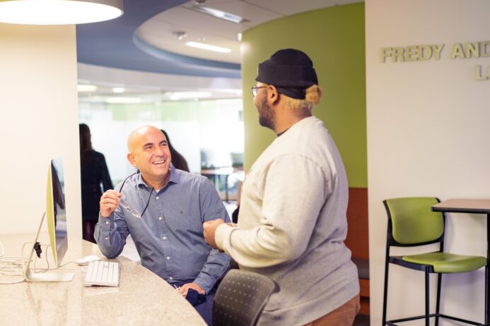 an advisor talking with a student in a brightly lit academic area