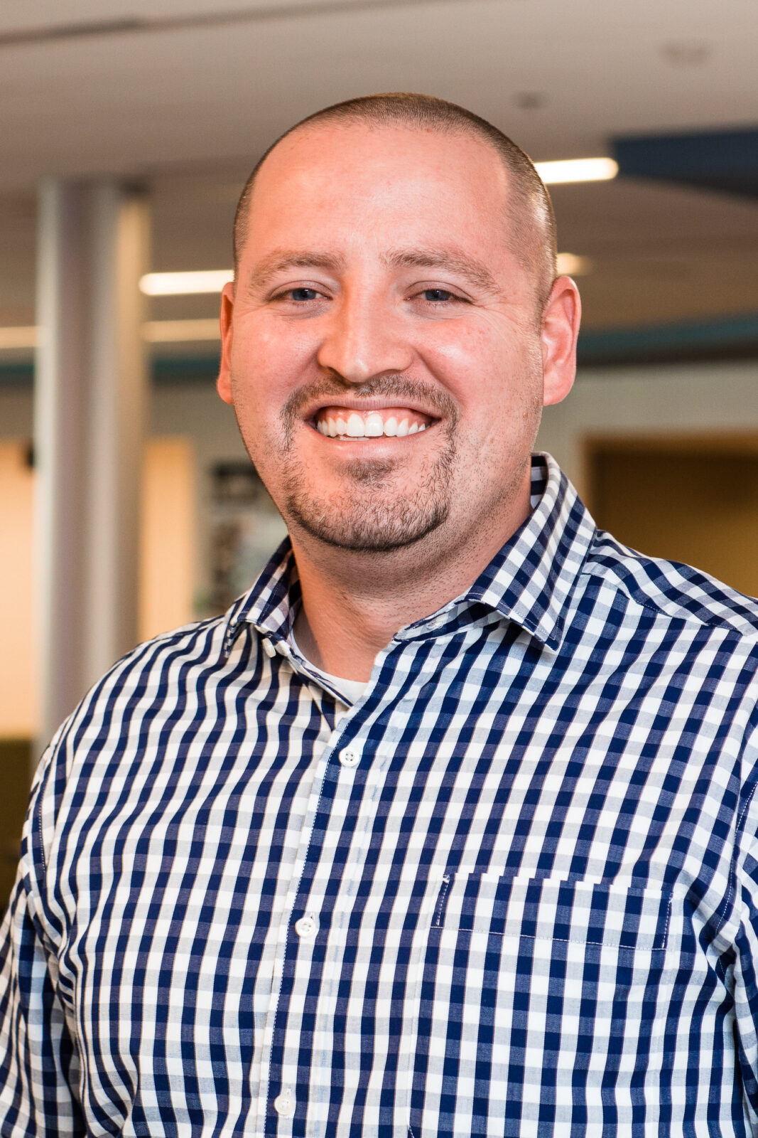 a man smiling wearing a plaid shirt