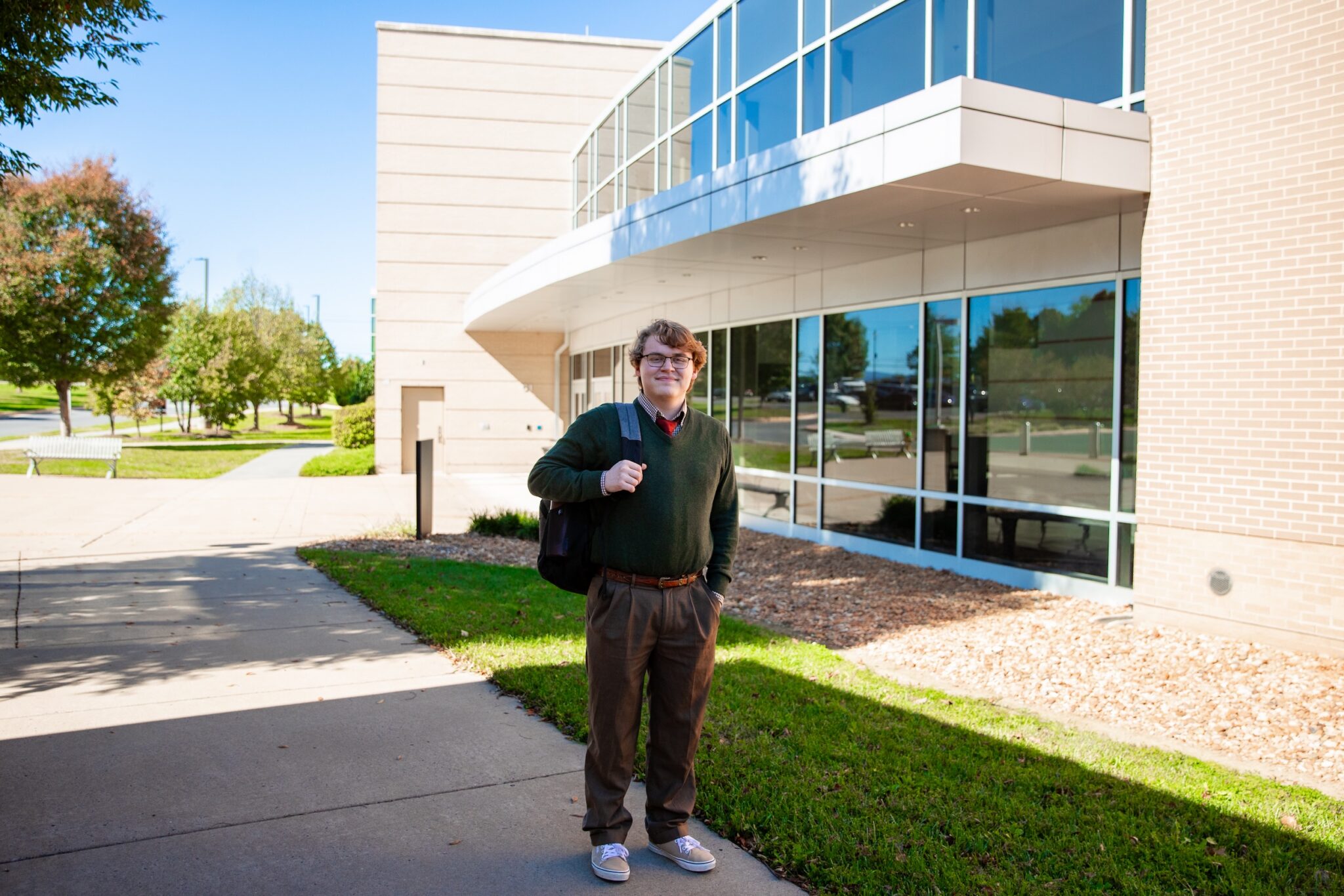 Adam Gagnon stands on a sidewalk outside a Laurel Ridge campus building with his backpack over one shoulder.